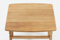 デンマークの建築家Henning Kjaernulf(ヘニング・ケアヌルフ)によってデザインされた、オーク無垢材のドロップリーフ式センターテーブルです。製造は高品質な家具で知られるEGモブラー社。無垢材ならではの美しい木目と、クラシカルで彫刻的な脚部のラインが印象的です。天板は両側に開閉式のリーフが備わっており、来客時や作業時には広げてスペースを拡張できるなど、実用性も兼ね備えています。高さ約51cmとやや高めの設計で、ソファ前に置いても手元が使いやすく、センターテーブルとして快適にお使いいただけます。必要に応じてサイドテーブルやティーテーブルとしても活躍する、用途の広い一台です。