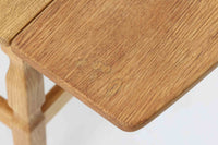 デンマークの建築家Henning Kjaernulf(ヘニング・ケアヌルフ)によってデザインされた、オーク無垢材のドロップリーフ式センターテーブルです。製造は高品質な家具で知られるEGモブラー社。無垢材ならではの美しい木目と、クラシカルで彫刻的な脚部のラインが印象的です。天板は両側に開閉式のリーフが備わっており、来客時や作業時には広げてスペースを拡張できるなど、実用性も兼ね備えています。高さ約51cmとやや高めの設計で、ソファ前に置いても手元が使いやすく、センターテーブルとして快適にお使いいただけます。必要に応じてサイドテーブルやティーテーブルとしても活躍する、用途の広い一台です。