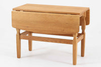 デンマークの建築家Henning Kjaernulf(ヘニング・ケアヌルフ)によってデザインされた、オーク無垢材のドロップリーフ式センターテーブルです。製造は高品質な家具で知られるEGモブラー社。無垢材ならではの美しい木目と、クラシカルで彫刻的な脚部のラインが印象的です。天板は両側に開閉式のリーフが備わっており、来客時や作業時には広げてスペースを拡張できるなど、実用性も兼ね備えています。テーブルの高さはやや高めの設計で、ソファ前に置いても手元が使いやすく、センターテーブルとして快適にお使いいただけます。必要に応じてサイドテーブルやティーテーブルとしても活躍する、用途の広い一台です。