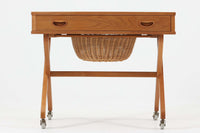 デンマーク製のビンテージ・ソーイングテーブルです。天板下には大きな引き出しが備わっており、裁縫道具や小物を収納するのに最適です。また、中央には籐製のバスケットが付属しており、毛糸や生地などを入れるのに便利な作りとなっています。脚部は交差したデザインが特徴的で、軽やかな印象を与えます。キャスター付きのため移動もスムーズで、リビングやワークスペースなどさまざまな場所で活躍します。シンプルながらも温かみのあるデザインは、北欧家具ならではの魅力。ソーイングテーブルとしてはもちろん、サイドテーブルとしてもお使いいただけます。