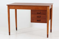 Borge mogensenデザインの小ぶりな片袖デスクは、モーエンセンらしい上質なオーク材が使用された美しいモデルです。デザインの特徴である引き出しの取手も、細部にわたるこだわりが感じられます。本体にはチーク材、脚にはビーチ材が使用され、デンマークの室内靴文化に配慮して、足元には汚れが目立たない濃い色味のチーク材がジョイントされています。洗練されたデザインと実用性を兼ね備えたこのデスクは、どんなインテリアにもマッチするアイテムです。