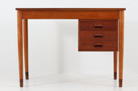 Borge mogensenデザインの小ぶりな片袖デスクは、モーエンセンらしい上質なオーク材が使用された美しいモデルです。デザインの特徴である引き出しの取手も、細部にわたるこだわりが感じられます。本体にはチーク材、脚にはビーチ材が使用され、デンマークの室内靴文化に配慮して、足元には汚れが目立たない濃い色味のチーク材がジョイントされています。洗練されたデザインと実用性を兼ね備えたこのデスクは、どんなインテリアにもマッチするアイテムです。