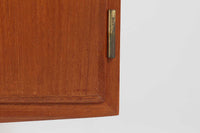 デンマークの家具メーカーHundevad & Co(ハンデバッド)による、Poul Hundevad(ポール・ハンデバッド)デザインのビンテージキャビネットです。美しい木目のチーク材が贅沢に使用され、北欧らしいシンプルで洗練された印象を与えます。両開きの扉内には左側に浅いトレイ状の引き出しが4段、右側には可動棚が2枚設けられており、機能性と収納力に優れた設計。扉の錠前は破損していたため施錠は出来ません。扉の開閉はボールキャッチ方式となっております。鍵は扉開閉用の取っ手として使用します。脚部にはすっきりとしたテーパードレッグが採用され、軽やかで洗練された佇まいが魅力です。リビングやダイニングなど幅広い空間で活躍する一台です。