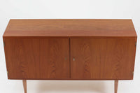 デンマークの家具メーカーHundevad & Co(ハンデバッド)による、Poul Hundevad(ポール・ハンデバッド)デザインのビンテージキャビネットです。美しい木目のチーク材が贅沢に使用され、北欧らしいシンプルで洗練された印象を与えます。両開きの扉内には左側に浅いトレイ状の引き出しが4段、右側には可動棚が2枚設けられており、機能性と収納力に優れた設計。扉の錠前は破損していたため施錠は出来ません。扉の開閉はボールキャッチ方式となっております。鍵は扉開閉用の取っ手として使用します。脚部にはすっきりとしたテーパードレッグが採用され、軽やかで洗練された佇まいが魅力です。リビングやダイニングなど幅広い空間で活躍する一台です。