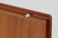 デンマークの家具メーカーHundevad & Co(ハンデバッド)による、Poul Hundevad(ポール・ハンデバッド)デザインのビンテージキャビネットです。美しい木目のチーク材が贅沢に使用され、北欧らしいシンプルで洗練された印象を与えます。両開きの扉内には左側に浅いトレイ状の引き出しが4段、右側には可動棚が2枚設けられており、機能性と収納力に優れた設計。扉の錠前は破損していたため施錠は出来ません。扉の開閉はボールキャッチ方式となっております。鍵は扉開閉用の取っ手として使用します。脚部にはすっきりとしたテーパードレッグが採用され、軽やかで洗練された佇まいが魅力です。リビングやダイニングなど幅広い空間で活躍する一台です。