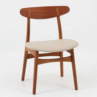 Hans J. Wegnerがデザインし、Carl Hansen & Son社によって製造されたCH30は、チーク材とオーク材を組み合わせた北欧ビンテージらしい温もりある佇まいと、背もたれに施されたフィンガージョイントがアクセントとなる美しいダイニングチェアです。丸みを帯びた背もたれと座面の柔らかなフォルムが身体に心地よくフィットし、長時間の着座でも快適な座り心地を提供します。座面はアイボリー系の合皮で張替済み、実用性と清潔感を兼ね備えており、日常使いから来客用まで幅広いシーンで活躍します。