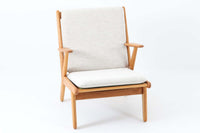 デンマークの国民的ブランドFDBによるビンテージのイージーチェア「J53」。デザイナーは北欧モダンデザインの旗手、Poul m. Volther(ポール・m・ヴォルター)。J53は同氏が手掛けたJシリーズの中でも希少なラウンジチェアタイプで、ゆったりとした座り心地とシンプルな構造美が魅力です。フレームには美しい木目を持つオーク材が使用されており、ナチュラルな風合いが北欧らしい温もりを感じさせます。背面の縦格子デザインや、柔らかくカーブしたアームの形状にも同氏ならではのディテールが感じられます。クッションは新たに張り替え済みで、清潔感のあるアイボリー系のファブリックが品のある印象を与えます。背面に「mADE IN DENmARK」およびFDBの刻印あり。