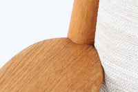 デンマークの国民的ブランドFDBによるビンテージのイージーチェア「J53」。デザイナーは北欧モダンデザインの旗手、Poul m. Volther(ポール・m・ヴォルター)。J53は同氏が手掛けたJシリーズの中でも希少なラウンジチェアタイプで、ゆったりとした座り心地とシンプルな構造美が魅力です。フレームには美しい木目を持つオーク材が使用されており、ナチュラルな風合いが北欧らしい温もりを感じさせます。背面の縦格子デザインや、柔らかくカーブしたアームの形状にも同氏ならではのディテールが感じられます。クッションは新たに張り替え済みで、清潔感のあるアイボリー系のファブリックが品のある印象を与えます。背面に「mADE IN DENmARK」およびFDBの刻印あり。