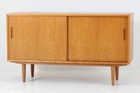 北欧より買い付けたサイドボードです。収納部の右側には、元々レコード収納用として設計されていたと思われる取り外し可能な縦仕切りがあり、幅の調整も可能です。棚板は取り外しできませんが、縦仕切りは全て取り外し可能で、大きなアイテムの収納にも対応できます。左側の収納部には、取り外しや可動が可能な引き出しが2杯備わっており、使い勝手も良好です。シンプルながらも高いクオリティを誇り、デンマークの家具デザイナーPoul Hundevadによってデザインされた本作は、デンマークの厳しい品質基準を満たした「DANISH FURNITUREmAKE'S CONTROL」のロゴシールが付いております。