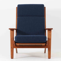 Hans J. Wegnerがデザインし、Getama社によって製造されたGe290Aは、現在では希少となったチーク材のフレームに深いブルーの張地が美しく調和した、ハイバック仕様のビンテージシングルソファです。緩やかに傾斜する背もたれと幅広のアームが身体を包み込むような快適な座り心地を実現し、日常に上質な寛ぎをもたらします。背面の格子状フレームや真鍮ビスなど、細部にまでウェグナーの美意識が宿り、北欧家具の名作としてリビングの主役にふさわしい存在感を放ちます。座面クッションにはスプリングが内包されていますが、背もたれにはウレタンのみが使用されています。