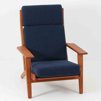 Hans J. Wegnerがデザインし、Getama社によって製造されたGe290Aは、現在では希少となったチーク材のフレームに深いブルーの張地が美しく調和した、ハイバック仕様のビンテージシングルソファです。緩やかに傾斜する背もたれと幅広のアームが身体を包み込むような快適な座り心地を実現し、日常に上質な寛ぎをもたらします。背面の格子状フレームや真鍮ビスなど、細部にまでウェグナーの美意識が宿り、北欧家具の名作としてリビングの主役にふさわしい存在感を放ちます。座面クッションにはスプリングが内包されていますが、背もたれにはウレタンのみが使用されています。