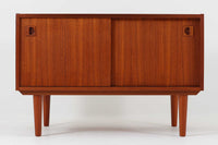 温かみのある木目が美しいチーク材を使用した、北欧ビンテージの小ぶりなローボードです。幅88cmとコンパクトながら、存在感のある佇まいで空間に上品なアクセントを加えます。引き戸の丸みを帯びた掘り込み取っ手や先細りの脚部など、シンプルながらも細部にまでこだわった北欧らしいデザインが魅力です。収納部には棚板が設けられていた形跡がありますが、現在は欠品しております。お気に入りの本や雑貨を飾るディスプレイ用としてもお楽しみいただけます。テレビ台やエントランスの収納など、多用途に活躍してくれる一台です。