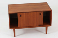 温かみのある木目が美しいチーク材を使用した、北欧ビンテージの小ぶりなローボードです。幅88cmとコンパクトながら、存在感のある佇まいで空間に上品なアクセントを加えます。引き戸の丸みを帯びた掘り込み取っ手や先細りの脚部など、シンプルながらも細部にまでこだわった北欧らしいデザインが魅力です。収納部には棚板が設けられていた形跡がありますが、現在は欠品しております。お気に入りの本や雑貨を飾るディスプレイ用としてもお楽しみいただけます。テレビ台やエントランスの収納など、多用途に活躍してくれる一台です。