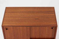 温かみのある木目が美しいチーク材を使用した、北欧ビンテージの小ぶりなローボードです。幅88cmとコンパクトながら、存在感のある佇まいで空間に上品なアクセントを加えます。引き戸の丸みを帯びた掘り込み取っ手や先細りの脚部など、シンプルながらも細部にまでこだわった北欧らしいデザインが魅力です。収納部には棚板が設けられていた形跡がありますが、現在は欠品しております。お気に入りの本や雑貨を飾るディスプレイ用としてもお楽しみいただけます。テレビ台やエントランスの収納など、多用途に活躍してくれる一台です。