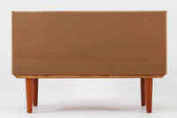 温かみのある木目が美しいチーク材を使用した、北欧ビンテージの小ぶりなローボードです。幅88cmとコンパクトながら、存在感のある佇まいで空間に上品なアクセントを加えます。引き戸の丸みを帯びた掘り込み取っ手や先細りの脚部など、シンプルながらも細部にまでこだわった北欧らしいデザインが魅力です。収納部には棚板が設けられていた形跡がありますが、現在は欠品しております。お気に入りの本や雑貨を飾るディスプレイ用としてもお楽しみいただけます。テレビ台やエントランスの収納など、多用途に活躍してくれる一台です。