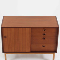 デンマーク製の小ぶりな北欧ビンテージボードで、チーク材とオーク材の組み合わせが上品な一台です。幅90cmとコンパクトながら、引き出し4杯とスライド扉付きの収納部を備え、実用性に優れています。丸いくり抜きの取っ手や直線的な脚部のデザインが軽快な印象を与え、どんな空間にも馴染みやすい造りです。背面の収納部には配線用の穴があり、オーディオや小型テレビ台としても活用可能です。経年により深みを増した木肌が、北欧家具ならではの味わいを感じさせます。
