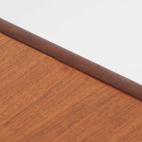 デンマーク製の小ぶりな北欧ビンテージボードで、チーク材とオーク材の組み合わせが上品な一台です。幅90cmとコンパクトながら、引き出し4杯とスライド扉付きの収納部を備え、実用性に優れています。丸いくり抜きの取っ手や直線的な脚部のデザインが軽快な印象を与え、どんな空間にも馴染みやすい造りです。背面の収納部には配線用の穴があり、オーディオや小型テレビ台としても活用可能です。経年により深みを増した木肌が、北欧家具ならではの味わいを感じさせます。