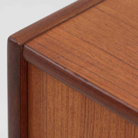 デンマーク製の小ぶりな北欧ビンテージボードで、チーク材とオーク材の組み合わせが上品な一台です。幅90cmとコンパクトながら、引き出し4杯とスライド扉付きの収納部を備え、実用性に優れています。丸いくり抜きの取っ手や直線的な脚部のデザインが軽快な印象を与え、どんな空間にも馴染みやすい造りです。背面の収納部には配線用の穴があり、オーディオや小型テレビ台としても活用可能です。経年により深みを増した木肌が、北欧家具ならではの味わいを感じさせます。