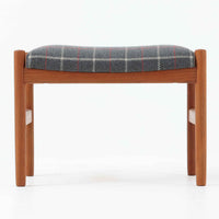 デンマーク製のこちらのスツールは、チーク材の温かみあるフレームに、日本メーカーのチェック柄ファブリックで張り替えを施した、北欧ビンテージ家具らしい洗練と実用性を兼ね備えた一脚です。脚部は丸棒を用いたシンプルな構造で、細部まで丁寧に仕上げられており、軽やかな佇まいの中に確かな安定感が感じられます。張地にはグレーベースに赤のラインがアクセントとなったチェック柄を採用し、空間に個性と落ち着きをもたらします。玄関やベッドサイド、オットマンとしての使用など幅広い用途に対応できるコンパクトなサイズ感も魅力です。また、裏面には「Danish Furnituremakers Control」ラベルが残されており、品質の高さを証明する一品です。経年により深まった木部の風合いと張地のコンビネーションが美しいスツールです。