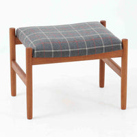 デンマーク製のこちらのスツールは、チーク材の温かみあるフレームに、日本メーカーのチェック柄ファブリックで張り替えを施した、北欧ビンテージ家具らしい洗練と実用性を兼ね備えた一脚です。脚部は丸棒を用いたシンプルな構造で、細部まで丁寧に仕上げられており、軽やかな佇まいの中に確かな安定感が感じられます。張地にはグレーベースに赤のラインがアクセントとなったチェック柄を採用し、空間に個性と落ち着きをもたらします。玄関やベッドサイド、オットマンとしての使用など幅広い用途に対応できるコンパクトなサイズ感も魅力です。また、裏面には「Danish Furnituremakers Control」ラベルが残されており、品質の高さを証明する一品です。経年により深まった木部の風合いと張地のコンビネーションが美しいスツールです。