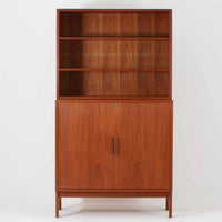 Bjerringbro Savvaerkによるチーク材キャビネットは、上下に分かれた構成と可動棚を備えた収納力の高さが魅力です。上段は3段のシェルフ、下段は珍しいポケットドア構造の扉内にA4サイズの書類が収納可能な引き出し型トレイが8段並び、書類や小物の整理に適しています。直線的で端正なフォルムと、チーク材の木目が美しく調和した佇まいは、北欧ビンテージらしい実用性と美しさを兼ね備えた逸品です。