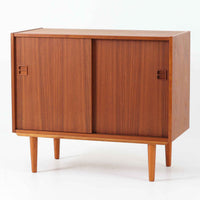 幅88cmとコンパクトなサイズ感が魅力のこちらのボードは、チーク材の温もりある質感と直線的なデザインが調和した北欧ビンテージ品です。前面にはスライド扉を備え、内部は左右に仕切られた収納スペースで、日用品の整理や見せたくない物の収納にも最適です。脚部にはテーパー加工が施され、軽やかな印象を与えつつ安定感も確保。省スペースに置けるため、玄関や寝室など限られた空間にもフィットし、日常に使いやすい一台です。