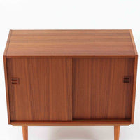 幅88cmとコンパクトなサイズ感が魅力のこちらのボードは、チーク材の温もりある質感と直線的なデザインが調和した北欧ビンテージ品です。前面にはスライド扉を備え、内部は左右に仕切られた収納スペースで、日用品の整理や見せたくない物の収納にも最適です。脚部にはテーパー加工が施され、軽やかな印象を与えつつ安定感も確保。省スペースに置けるため、玄関や寝室など限られた空間にもフィットし、日常に使いやすい一台です。