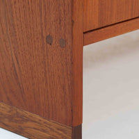 Hans J. Wegner(ハンス・J・ウェグナー)によってデザインされ、RY Mobler社により製造されたこちらのキャビネットは、美しいチーク材と実用的な構造が融合した北欧ビンテージ家具の名作です。扉にはチーク材特有の深い木目が活かされ、中央の控えめな金属製ハンドルがアクセントとなっています。内部は可動棚付きの2室構成で、食器類や書類、小物の整理にも適した収納力を備えています。注目すべきは、足摺にあたる下部のパーツにオーク材が使用されている点で、異なる木材の組み合わせが上質なコントラストを生み出しています。背面には「RY」ロゴと「27 APR 1959」のスタンプが残っており、当時のオリジナルであることが確認できます。リビングやダイニング、書斎などさまざまな空間で、温もりと凛とした佇まいを演出してくれる北欧ビンテージ家具らしい一台です。