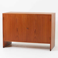 Hans J. Wegner(ハンス・J・ウェグナー)によってデザインされ、RY Mobler社により製造されたこちらのキャビネットは、美しいチーク材と実用的な構造が融合した北欧ビンテージ家具の名作です。扉にはチーク材特有の深い木目が活かされ、中央の控えめな金属製ハンドルがアクセントとなっています。内部は可動棚付きの2室構成で、食器類や書類、小物の整理にも適した収納力を備えています。注目すべきは、足摺にあたる下部のパーツにオーク材が使用されている点で、異なる木材の組み合わせが上質なコントラストを生み出しています。背面には「RY」ロゴと「27 APR 1959」のスタンプが残っており、当時のオリジナルであることが確認できます。リビングやダイニング、書斎などさまざまな空間で、温もりと凛とした佇まいを演出してくれる北欧ビンテージ家具らしい一台です。