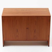 Hans J. Wegner(ハンス・J・ウェグナー)によってデザインされ、RY Mobler社により製造されたこちらのキャビネットは、美しいチーク材と実用的な構造が融合した北欧ビンテージ家具の名作です。扉にはチーク材特有の深い木目が活かされ、中央の控えめな金属製ハンドルがアクセントとなっています。内部は可動棚付きの2室構成で、食器類や書類、小物の整理にも適した収納力を備えています。注目すべきは、足摺にあたる下部のパーツにオーク材が使用されている点で、異なる木材の組み合わせが上質なコントラストを生み出しています。背面には「RY」ロゴと「27 APR 1959」のスタンプが残っており、当時のオリジナルであることが確認できます。リビングやダイニング、書斎などさまざまな空間で、温もりと凛とした佇まいを演出してくれる北欧ビンテージ家具らしい一台です。