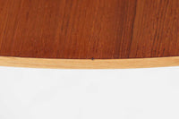 Holger Georg Jensen(ホルガー・ジョージ・イェンセン)によってデザインされ、Kubus moblerから製造されたデンマーク製ビンテージのサイドテーブルです。有機的な曲線を描く天板と、それを支える3本脚の構造が美しいバランスを保っています。天板下には同形状の棚板が設けられており、雑誌や小物の収納にも便利です。素材には艶やかなチーク材が用いられ、天板の木目の美しさも際立っています。北欧モダンを感じさせる上品な佇まいで、ソファサイドやベッドサイドにおすすめの一台です。