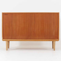 オーク材の美しい木目と柔らかな色味が魅力のこちらのボードは、幅120cmと使い勝手の良いサイズ感で、北欧ビンテージらしい洗練された佇まいが魅力です。内部には可動棚とフェルト付きの浅型引き出しが備えられ、日用品や小物の整理に最適。彫り込み式の取手やテーパードレッグなど、細部にまで配慮された上質な造りが光ります。販売店ラベルとして「Nr. Uttrup Boligmontering」が残されており、当時の流通背景を感じさせる一点物のアイテムです。