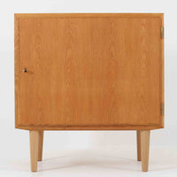 Poul Hundevadがデザインし、Hundevad & Co社から製造されたこちらのキャビネットは、上質なオーク材を用いた小ぶりな北欧ビンテージ品で、すっきりとした面構えと繊細な脚部が印象的な一台です。鍵付きの開き戸を備え、内部には棚板が設けられており、収納家具としての実用性に加え、空間にナチュラルで落ち着いた佇まいをもたらします。なお、脚部は後年に交換されている可能性がありますが、全体の雰囲気を損なわない自然な仕上がりです。
