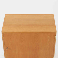 Poul Hundevadがデザインし、Hundevad & Co社から製造されたこちらのキャビネットは、上質なオーク材を用いた小ぶりな北欧ビンテージ品で、すっきりとした面構えと繊細な脚部が印象的な一台です。鍵付きの開き戸を備え、内部には棚板が設けられており、収納家具としての実用性に加え、空間にナチュラルで落ち着いた佇まいをもたらします。なお、脚部は後年に交換されている可能性がありますが、全体の雰囲気を損なわない自然な仕上がりです。