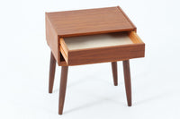 デンマークで製造されたヴィンテージのサイドチェスト。温もりのあるチーク材を用いた本体に、先細りの丸脚を組み合わせた軽やかな佇まいが魅力です。引き出し1杯に加え、下部にはオープンスペースを備えており、リモコンや文庫本などをすぐに取り出せる実用的な構造。天板や側面にはすっきりとした面取りが施され、シンプルなデザインの中に丁寧な仕事が感じられます。北欧らしいあたたかみと実用性を兼ね備えた一台。ベッドサイドはもちろん、リビングや玄関先など、暮らしのさまざまな場面で活躍します。