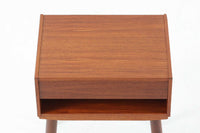 デンマークで製造されたヴィンテージのサイドチェスト。温もりのあるチーク材を用いた本体に、先細りの丸脚を組み合わせた軽やかな佇まいが魅力です。引き出し1杯に加え、下部にはオープンスペースを備えており、リモコンや文庫本などをすぐに取り出せる実用的な構造。天板や側面にはすっきりとした面取りが施され、シンプルなデザインの中に丁寧な仕事が感じられます。北欧らしいあたたかみと実用性を兼ね備えた一台。ベッドサイドはもちろん、リビングや玄関先など、暮らしのさまざまな場面で活躍します。