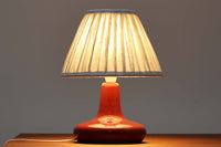 デンマークの照明ブランドLe Klint(レ・クリント)のテーブルランプで、デザイナーはOle Boggild(オーレ・ボギル)。艶やかなレッドの釉薬が美しく、ふっくらと丸みを帯びたフォルムが愛らしくも上品な印象を与えます。シェードはLe Klint社製ではありませんが、新品のリネン製プリーツシェードを合わせており、クラシカルな佇まいと柔らかな光を演出します。北欧らしい温かみと洗練された存在感を持ち、ベッドサイドやリビングのアクセントとして取り入れやすい一灯です。