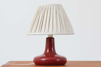 デンマークの照明ブランドLe Klint(レ・クリント)のテーブルランプで、デザイナーはOle Boggild(オーレ・ボギル)。艶やかなレッドの釉薬が美しく、ふっくらと丸みを帯びたフォルムが愛らしくも上品な印象を与えます。シェードはLe Klint社製ではありませんが、新品のリネン製プリーツシェードを合わせており、クラシカルな佇まいと柔らかな光を演出します。北欧らしい温かみと洗練された存在感を持ち、ベッドサイドやリビングのアクセントとして取り入れやすい一灯です。