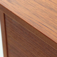 チーク材を用いたこちらの2段チェストは、緩やかにカーブした天板と舟形の引き手が特徴的な北欧ビンテージ家具です。幅64cmとコンパクトながらも引き出し2杯と下部の棚板を備え、収納力とディスプレイ性を兼ね備えています。テーパー脚が軽やかな印象を与え、ベッドサイドやリビングのサイドテーブルとしても活躍。年月を経た木肌の温かみが、空間に落ち着きと味わい深い存在感をもたらす一品です。