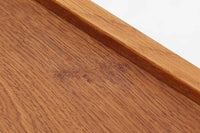 デンマークを代表する家具デザイナー、Hans J. Wegner(ハンス・J・ウェグナー)によってデザインされた、Ry mobler社製のビンテージサイドテーブルです。素材にはあたたかみのあるオーク材が使用されており、北欧らしいシンプルで機能的な美しさが感じられます。天板には縁に立ち上がりが設けられており、小物が転がり落ちにくい実用的な仕様。引き出しとオープンスペースが組み合わされたデザインで、ベッドサイドやソファ横、玄関周りなど様々なシーンで活躍します。無駄のないフォルムと丸脚の柔らかな佇まいが魅力で、ウェグナーデザインならではの美しいバランスが光る一台です。背板には、同モデルとしては珍しくオーク材ではなくmDFと思われる素材が使用されています。また、天板には目立つ傷がございますため、その点を考慮した価格設定とさせていただいております。