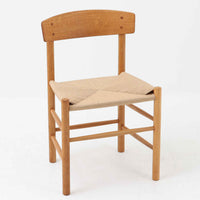 デンマークを代表するデザイナー、Borge MogensenによってFDBのためにデザインされたJ39チェアは、オーク材の丸脚と座面に丁寧に編み込まれたペーパーコードが特徴の、素朴ながらも完成度の高い北欧ビンテージチェアです。農村のキッチンチェアをルーツに持つそのデザインは、無駄を省いた潔い構造と機能美が融合し、空間に凛とした佇まいをもたらします。ダイニングはもちろん、ワークチェアやアクセントチェアとしても重宝する一脚です。