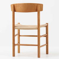 デンマークを代表するデザイナー、Borge MogensenによってFDBのためにデザインされたJ39チェアは、オーク材の丸脚と座面に丁寧に編み込まれたペーパーコードが特徴の、素朴ながらも完成度の高い北欧ビンテージチェアです。農村のキッチンチェアをルーツに持つそのデザインは、無駄を省いた潔い構造と機能美が融合し、空間に凛とした佇まいをもたらします。ダイニングはもちろん、ワークチェアやアクセントチェアとしても重宝する一脚です。