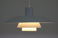 北欧照明の巨匠Poul Henningsenによってデザインされた「PH4」ペンダントライト。Louis Poulsen社製で、光を効率よく拡散させる3枚シェード構造が特徴。内側にオレンジのリフレクターを備えており、暖かく落ち着いた光を演出します。シェード表面には経年に伴う擦れや細かい傷、塗装の薄れが見られますが、ビンテージらしい味わいを感じられる一品です。リビングやダイニング、カウンター上などにおすすめのサイズ感です。