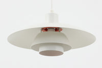 北欧照明の巨匠Poul Henningsenによってデザインされた「PH4」ペンダントライト。Louis Poulsen社製で、光を効率よく拡散させる3枚シェード構造が特徴。内側にオレンジのリフレクターを備えており、暖かく落ち着いた光を演出します。シェード表面には経年に伴う擦れや細かい傷、塗装の薄れが見られますが、ビンテージらしい味わいを感じられる一品です。リビングやダイニング、カウンター上などにおすすめのサイズ感です。