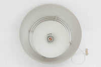 デンマークを代表する建築家・デザイナー、アルネ・ヤコブセンによってデザインされた「AJロイヤル」ペンダントライト。Louis Poulsen(ルイスポールセン)社より発表され、建築物と調和するミニマルなフォルムが特徴的です。こちらは直径50cmのホワイトカラーのモデルで、1958年に設計されたコペンハーゲンのSASロイヤルホテルのために開発されたシリーズのひとつ。上部のルーバー構造からも光が漏れる設計により、下方向だけでなく柔らかく空間全体を照らします。モダニズムの美学が息づく名作照明でありながら、日常の空間にもすっと馴染む柔らかな存在感が魅力です。ヴィンテージ品のため、シェードには擦り傷や小さな塗装剥がれ、内側に若干のサビが見られますが、使用には問題ありません。全体としては良好なコンディションを保っており、ヴィンテージならではの風合いをお楽しみいただけます。コードおよびソケットは国内基準に適合した仕様に交換済みで、すぐにご使用いただけます。