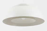 デンマークを代表する建築家・デザイナー、アルネ・ヤコブセンによってデザインされた「AJロイヤル」ペンダントライト。Louis Poulsen(ルイスポールセン)社より発表され、建築物と調和するミニマルなフォルムが特徴的です。こちらは直径50cmのホワイトカラーのモデルで、1958年に設計されたコペンハーゲンのSASロイヤルホテルのために開発されたシリーズのひとつ。上部のルーバー構造からも光が漏れる設計により、下方向だけでなく柔らかく空間全体を照らします。モダニズムの美学が息づく名作照明でありながら、日常の空間にもすっと馴染む柔らかな存在感が魅力です。ヴィンテージ品のため、シェードには擦り傷や小さな塗装剥がれ、内側に若干のサビが見られますが、使用には問題ありません。全体としては良好なコンディションを保っており、ヴィンテージならではの風合いをお楽しみいただけます。コードおよびソケットは国内基準に適合した仕様に交換済みで、すぐにご使用いただけます。