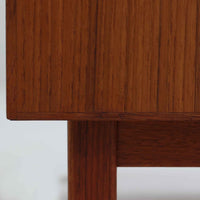 チーク材を使用したスウェーデン製のディスプレイシェルフです。上段は収納力のある可動棚付きのオープンスペース、下段には引き出し4杯と扉収納が備えられており、実用性とデザイン性を兼ね備えた構成です。シンプルな取手の意匠や直線的な脚部が北欧家具らしい洗練を感じさせ、経年により深みを増したチークの色合いが空間に温かみを与えます。リビングや書斎での本や雑貨の収納・展示におすすめのビンテージアイテムです。