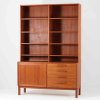 Nils JonssonがTroeds社のためにデザインした「Domi Monté」モデルのディスプレイシェルフ。チーク材を贅沢に使用し、温かみのある木肌と洗練されたフォルムが魅力の一台です。上部には高さ調整が可能な可動棚が8枚備わり、本やオブジェのディスプレイに柔軟に対応。下部には扉付き収納と仕切り付きの引き出しが配されており、実用性にも優れます。背面にはTroeds社の刻印が残されており、スウェーデン製ビンテージ家具としての確かな出自を物語ります。空間に落ち着きと上質な雰囲気を添える、北欧モダンらしい逸品です。