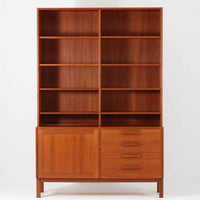 Nils JonssonがTroeds社のためにデザインした「Domi Monté」モデルのディスプレイシェルフ。チーク材を贅沢に使用し、温かみのある木肌と洗練されたフォルムが魅力の一台です。上部には高さ調整が可能な可動棚が8枚備わり、本やオブジェのディスプレイに柔軟に対応。下部には扉付き収納と仕切り付きの引き出しが配されており、実用性にも優れます。背面にはTroeds社の刻印が残されており、スウェーデン製ビンテージ家具としての確かな出自を物語ります。空間に落ち着きと上質な雰囲気を添える、北欧モダンらしい逸品です。