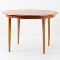 チーク材の天板とオーク材の脚部が美しく調和したこちらの円形エクステンションダイニングテーブルは、デンマーク製ならではの丁寧な仕上げと実用性が魅力の北欧ビンテージ家具です。直径110cmの円形天板は、中央に拡張板を2枚追加することで広々としたオーバル型に変化し、来客時やホームパーティーなどにも柔軟に対応できます。細身のテーパー脚が軽やかな印象を与え、温かみのある木の表情が空間に自然と溶け込む逸品です。